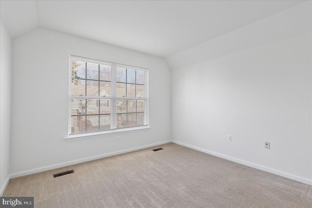 empty room with vaulted ceiling and light carpet