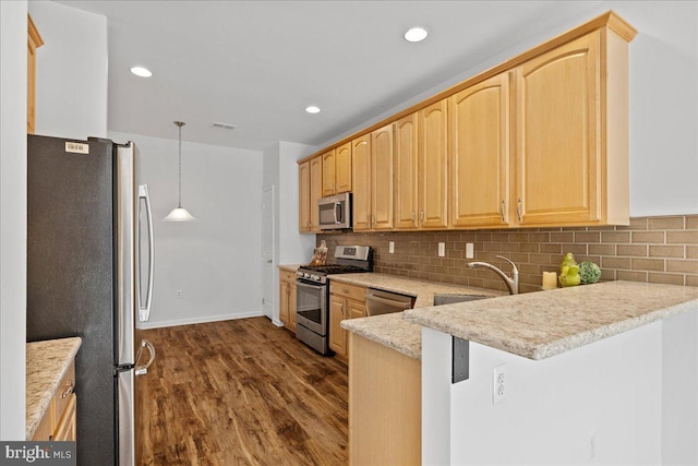 kitchen featuring decorative backsplash, hanging light fixtures, kitchen peninsula, stainless steel appliances, and dark wood-type flooring