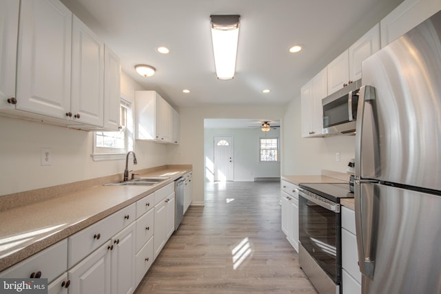 kitchen featuring stainless steel appliances, white cabinetry, a healthy amount of sunlight, and light hardwood / wood-style flooring