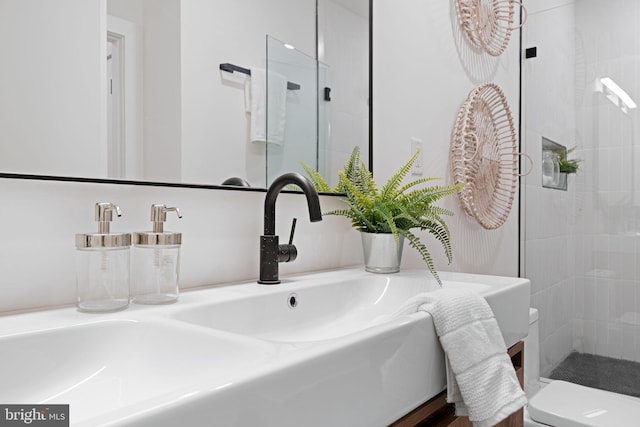 bathroom with a tile shower, sink, and toilet