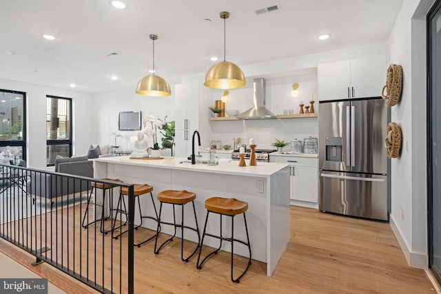 kitchen featuring white cabinets, stainless steel appliances, wall chimney exhaust hood, and sink