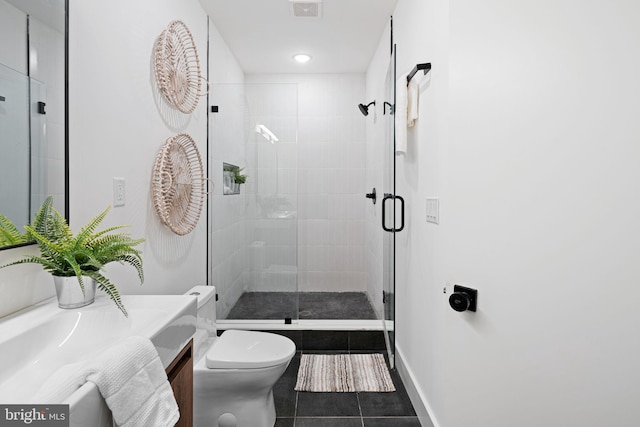 bathroom featuring tile patterned floors, a shower with door, vanity, and toilet