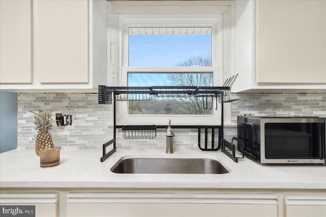 room details with backsplash, light stone counters, sink, and white cabinets