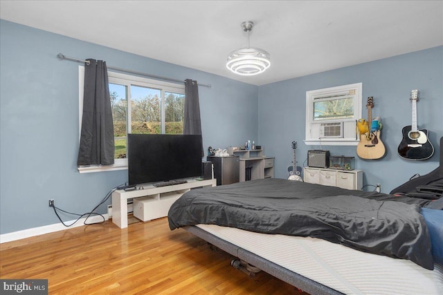 bedroom featuring cooling unit, light wood-type flooring, and multiple windows