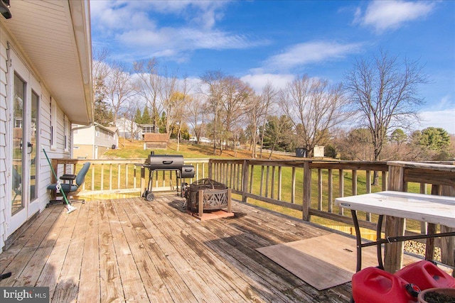 wooden deck with a lawn, grilling area, and a fire pit