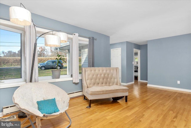 living area with light wood-type flooring, a baseboard radiator, and a healthy amount of sunlight