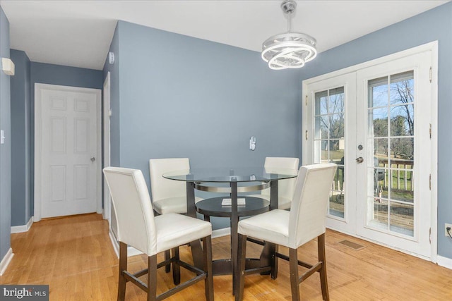 dining room featuring a chandelier, french doors, and light hardwood / wood-style flooring