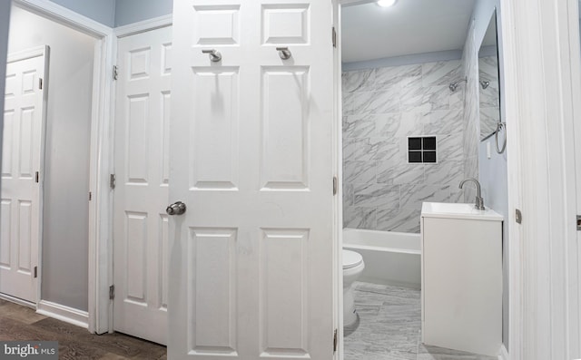 full bathroom featuring hardwood / wood-style floors, toilet, washtub / shower combination, and sink