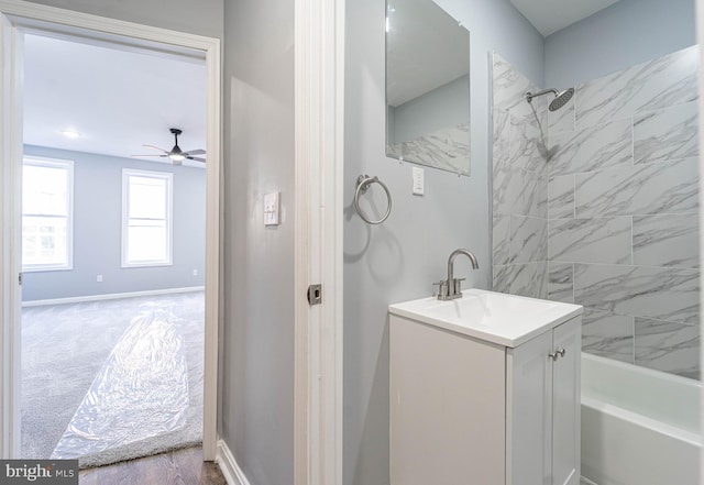 bathroom featuring wood-type flooring, vanity, tiled shower / bath combo, and ceiling fan