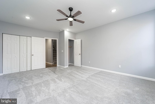 unfurnished bedroom featuring light carpet, a closet, and ceiling fan