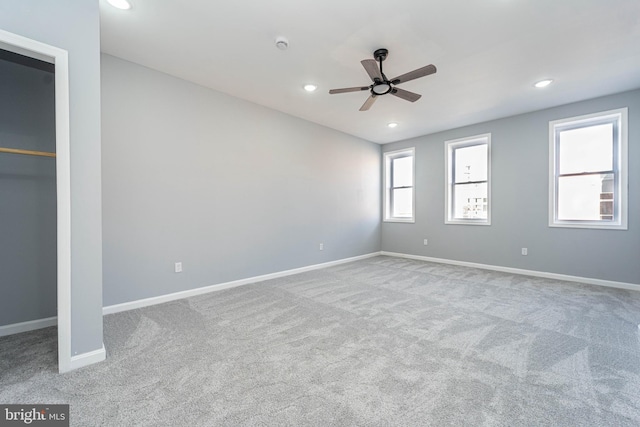 unfurnished bedroom featuring light carpet, a spacious closet, and ceiling fan