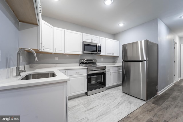 kitchen with white cabinetry, sink, light wood-type flooring, and appliances with stainless steel finishes