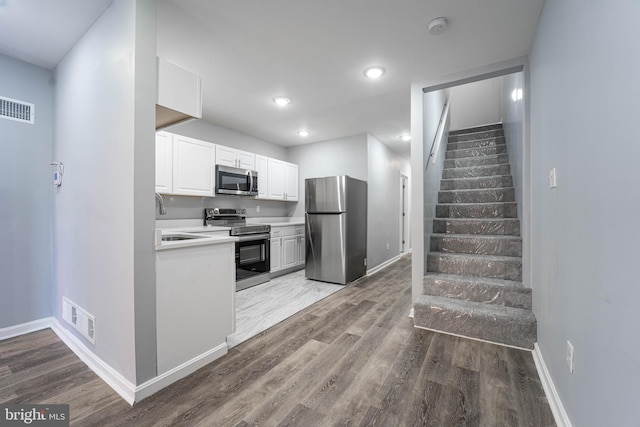 kitchen featuring hardwood / wood-style floors, white cabinets, stainless steel appliances, and sink