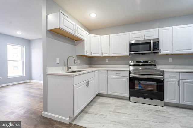 kitchen featuring appliances with stainless steel finishes, light hardwood / wood-style flooring, white cabinetry, and sink