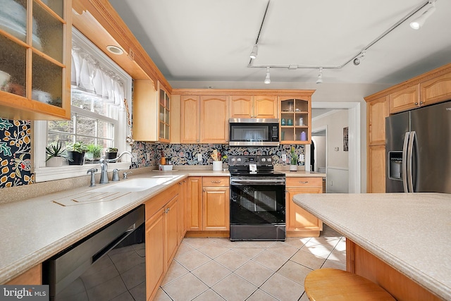 kitchen with sink, tasteful backsplash, track lighting, light tile patterned floors, and black appliances