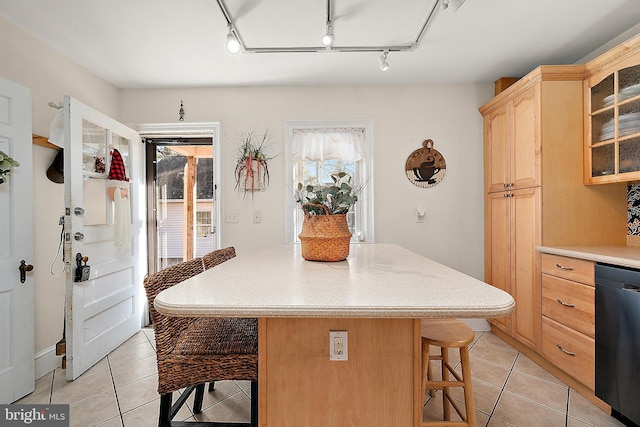 kitchen featuring a breakfast bar area, light brown cabinets, a healthy amount of sunlight, and black dishwasher