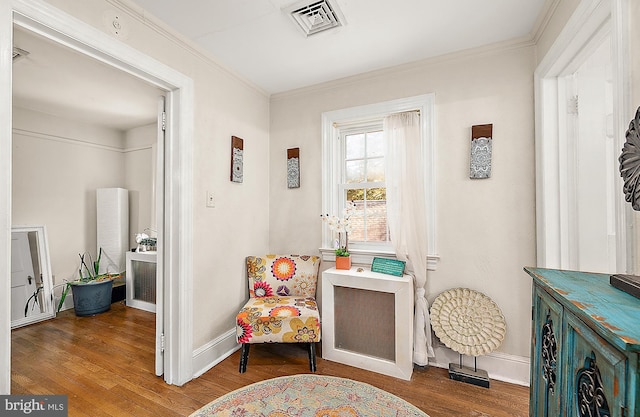 sitting room with wood-type flooring and ornamental molding