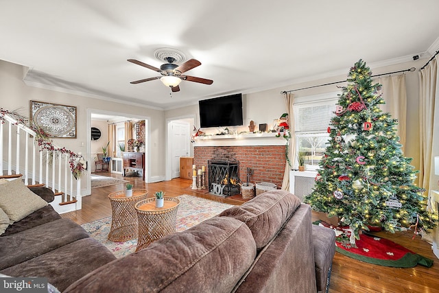 living room with a fireplace, hardwood / wood-style floors, ceiling fan, and ornamental molding