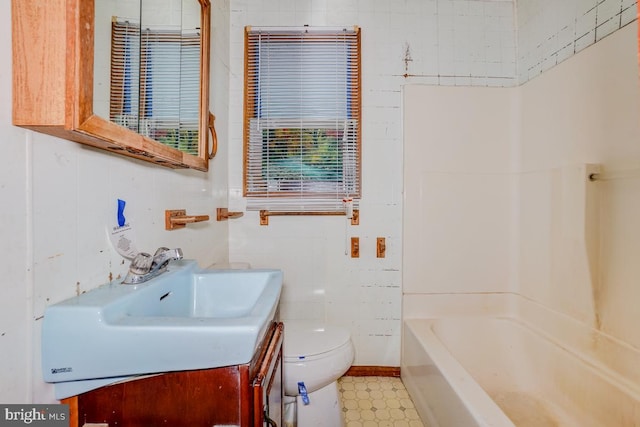 bathroom with vanity, a tub to relax in, and toilet