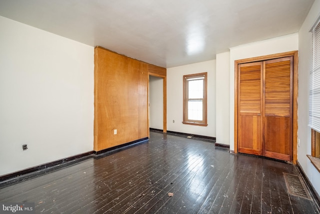 unfurnished bedroom featuring a closet and dark wood-type flooring