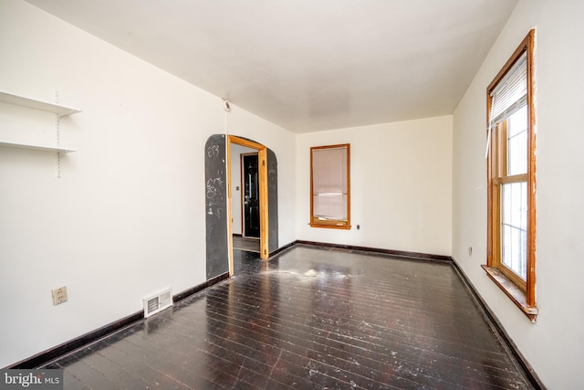 empty room with a wealth of natural light and dark wood-type flooring