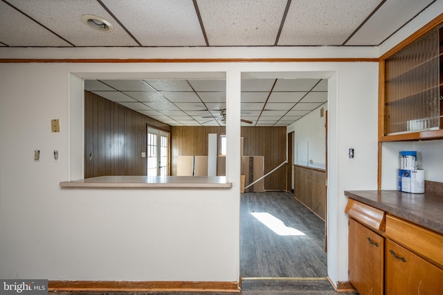 kitchen featuring wood walls, hardwood / wood-style floors, and a drop ceiling