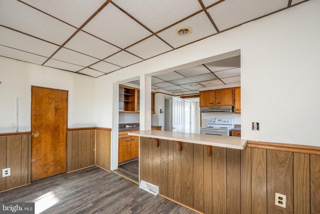 kitchen featuring a paneled ceiling, dark wood-type flooring, electric stove, wooden walls, and kitchen peninsula