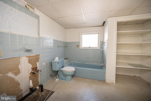 bathroom featuring a drop ceiling, toilet, and tile walls