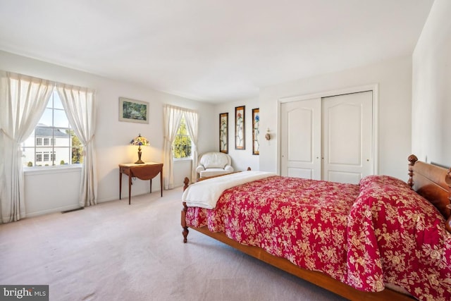 bedroom featuring multiple windows, a closet, and light colored carpet