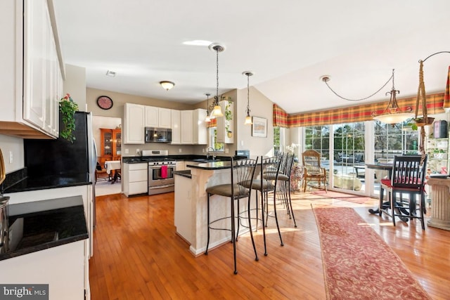 kitchen with a kitchen bar, kitchen peninsula, stainless steel appliances, sink, and white cabinets