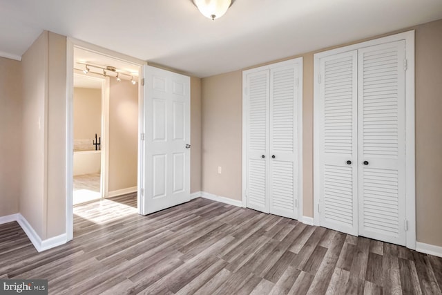 unfurnished bedroom featuring hardwood / wood-style floors and multiple closets