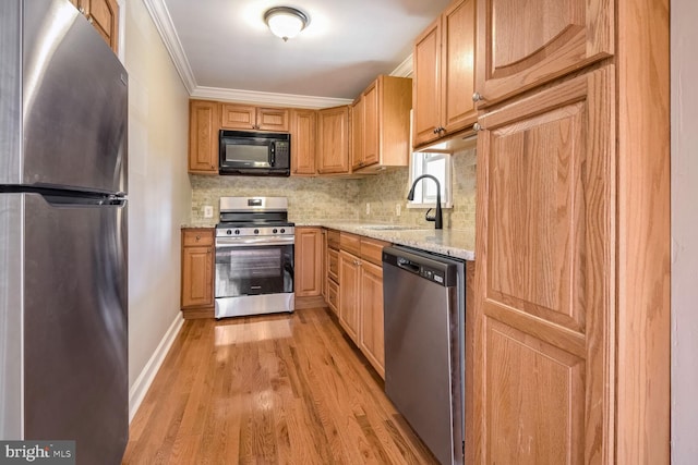 kitchen featuring sink, light stone counters, crown molding, light hardwood / wood-style floors, and appliances with stainless steel finishes