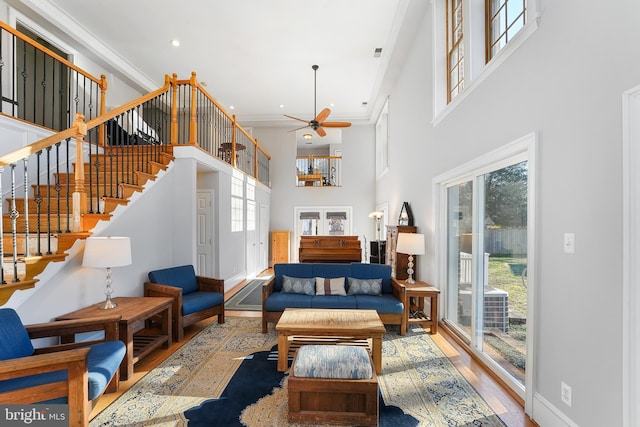 interior space featuring ceiling fan, crown molding, wood-type flooring, and a high ceiling