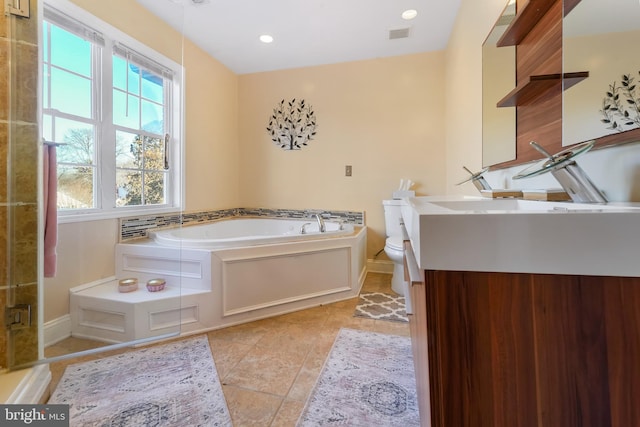 bathroom with tile patterned floors, a tub to relax in, vanity, and toilet