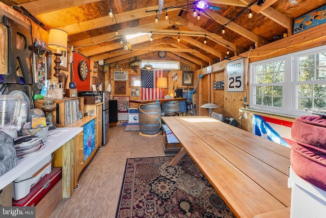 interior space with lofted ceiling with beams, light hardwood / wood-style floors, a wall mounted AC, and wood walls