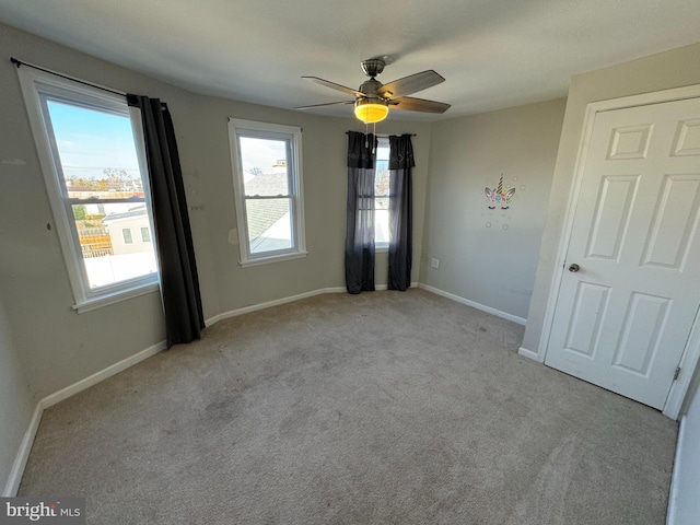 carpeted spare room featuring plenty of natural light and ceiling fan