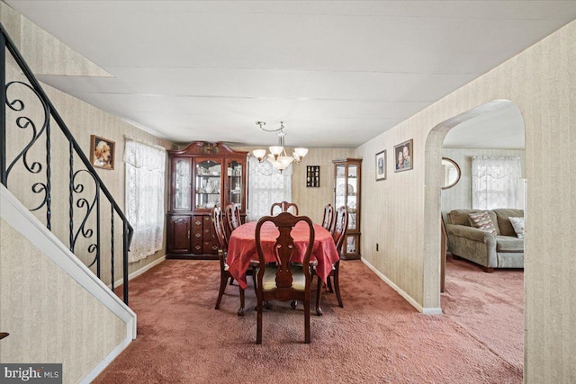 carpeted dining area featuring an inviting chandelier