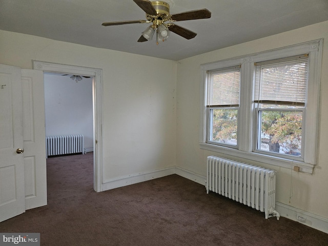 unfurnished room featuring dark colored carpet, radiator heating unit, and ceiling fan