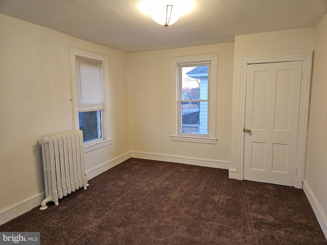 empty room featuring radiator and dark colored carpet