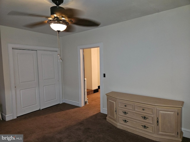 unfurnished bedroom featuring ceiling fan, dark carpet, and a closet