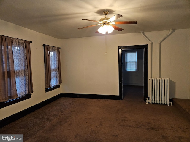 unfurnished room featuring ceiling fan, radiator heating unit, and dark colored carpet