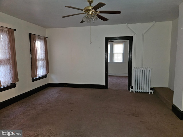 unfurnished room with dark colored carpet, radiator heating unit, and ceiling fan