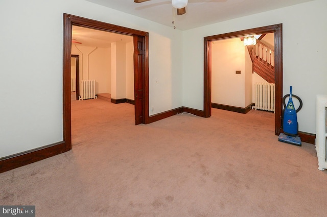 carpeted empty room featuring ceiling fan and radiator