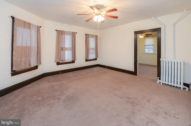 empty room featuring light carpet, radiator, and ceiling fan