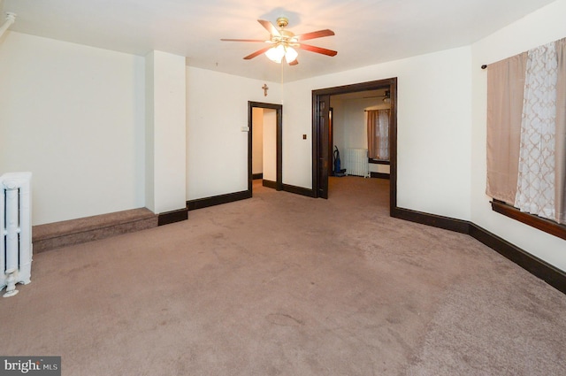 empty room featuring ceiling fan, light colored carpet, and radiator