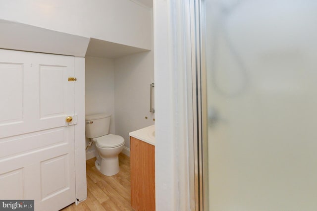 bathroom with vanity, toilet, wood-type flooring, and a shower with shower door