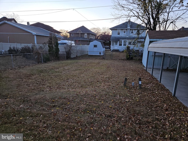 yard at dusk featuring a carport and a storage shed