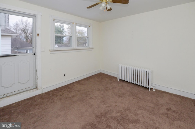 carpeted empty room featuring ceiling fan and radiator heating unit