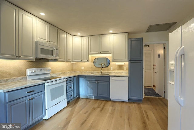 kitchen featuring light stone countertops, sink, backsplash, white appliances, and light wood-type flooring