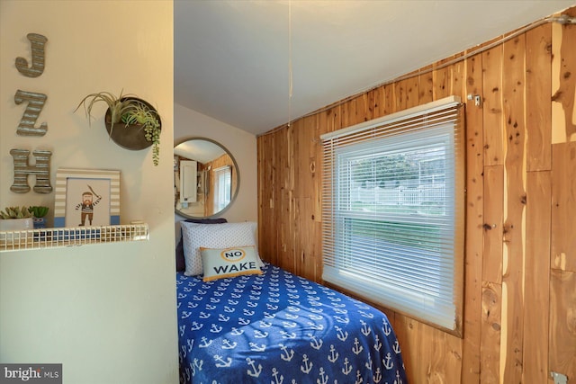 bedroom with lofted ceiling and wooden walls